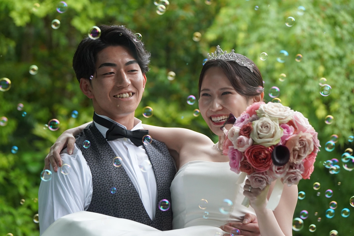 シャボン玉が舞う中で笑顔を見せる新郎新婦